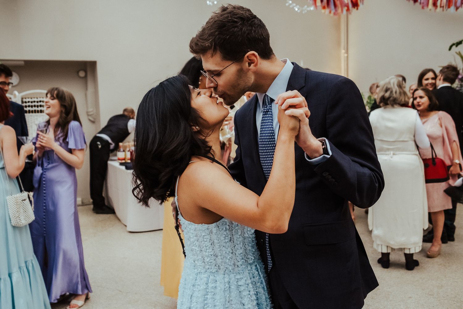 Couples dancing together at a wedding reception in a light-filled room.