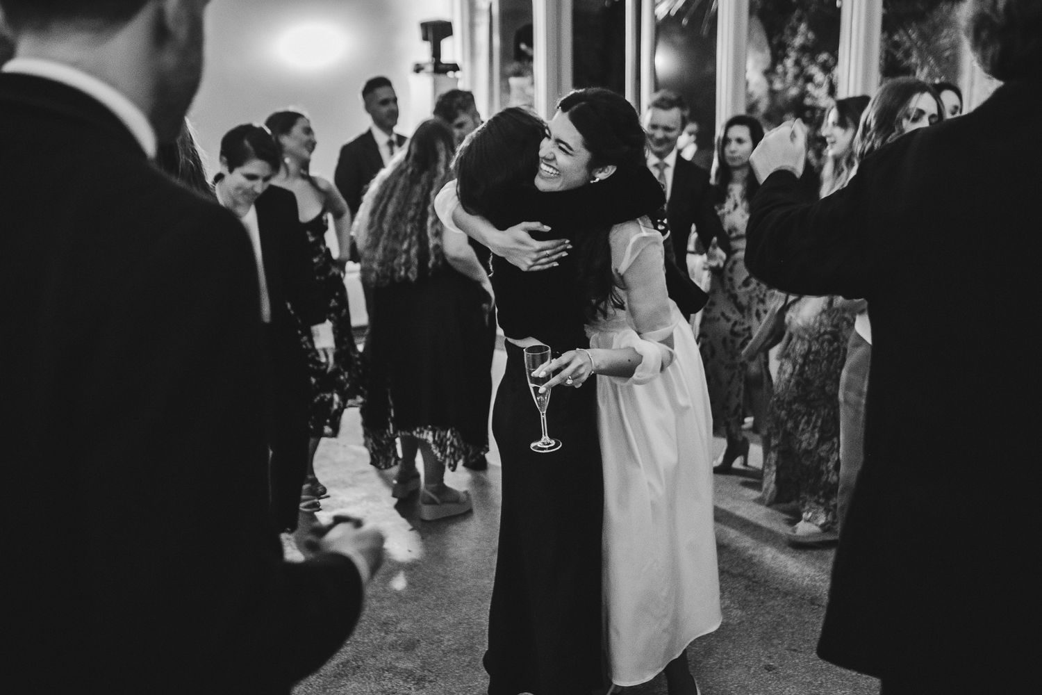 Black and white photo of guests embracing during an elegant evening reception.