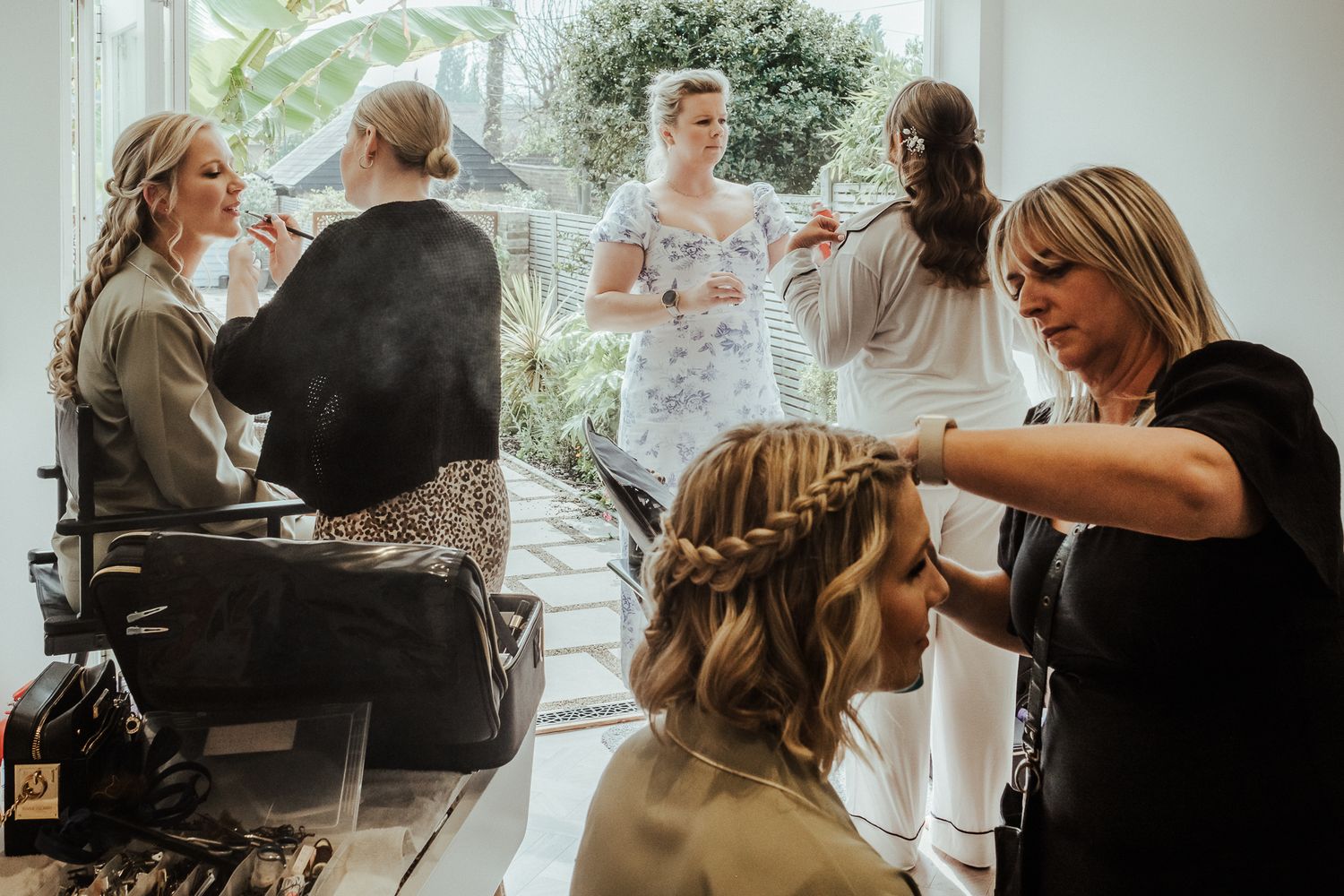 Behind the scenes of wedding preparations with stylists working in a sunlit room.