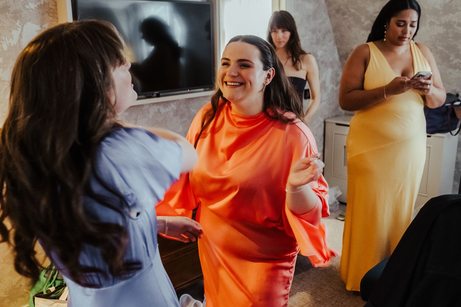 Wedding party members in vibrant orange and blue outfits mingling indoors.