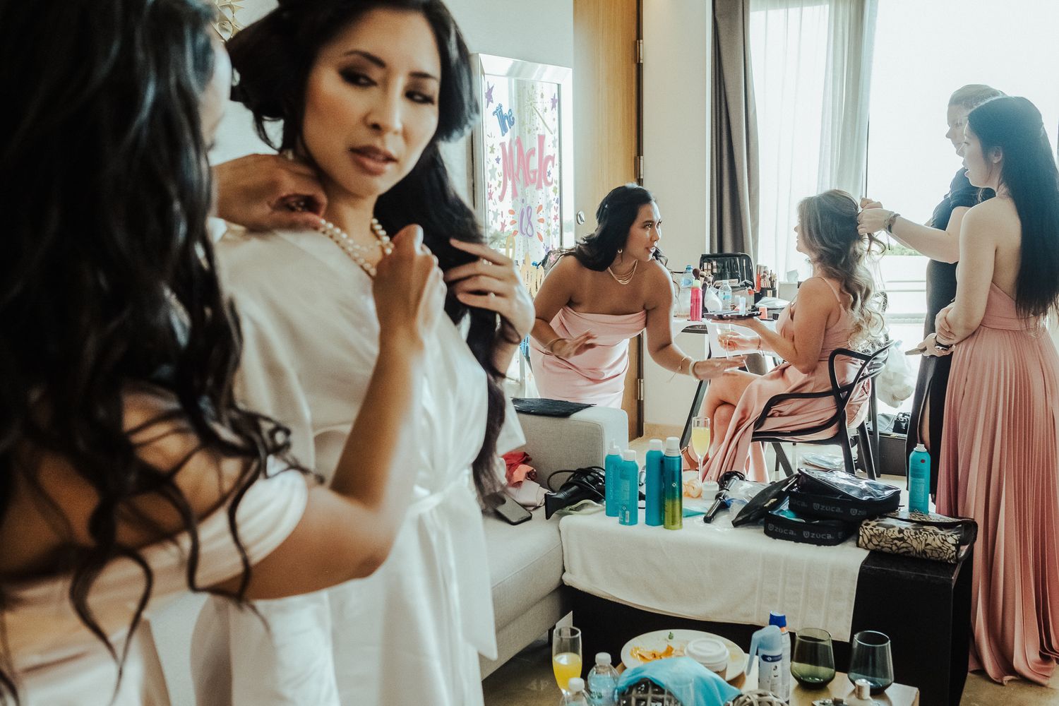 Wedding preparation scene with bridesmaids getting ready in a busy dressing room.