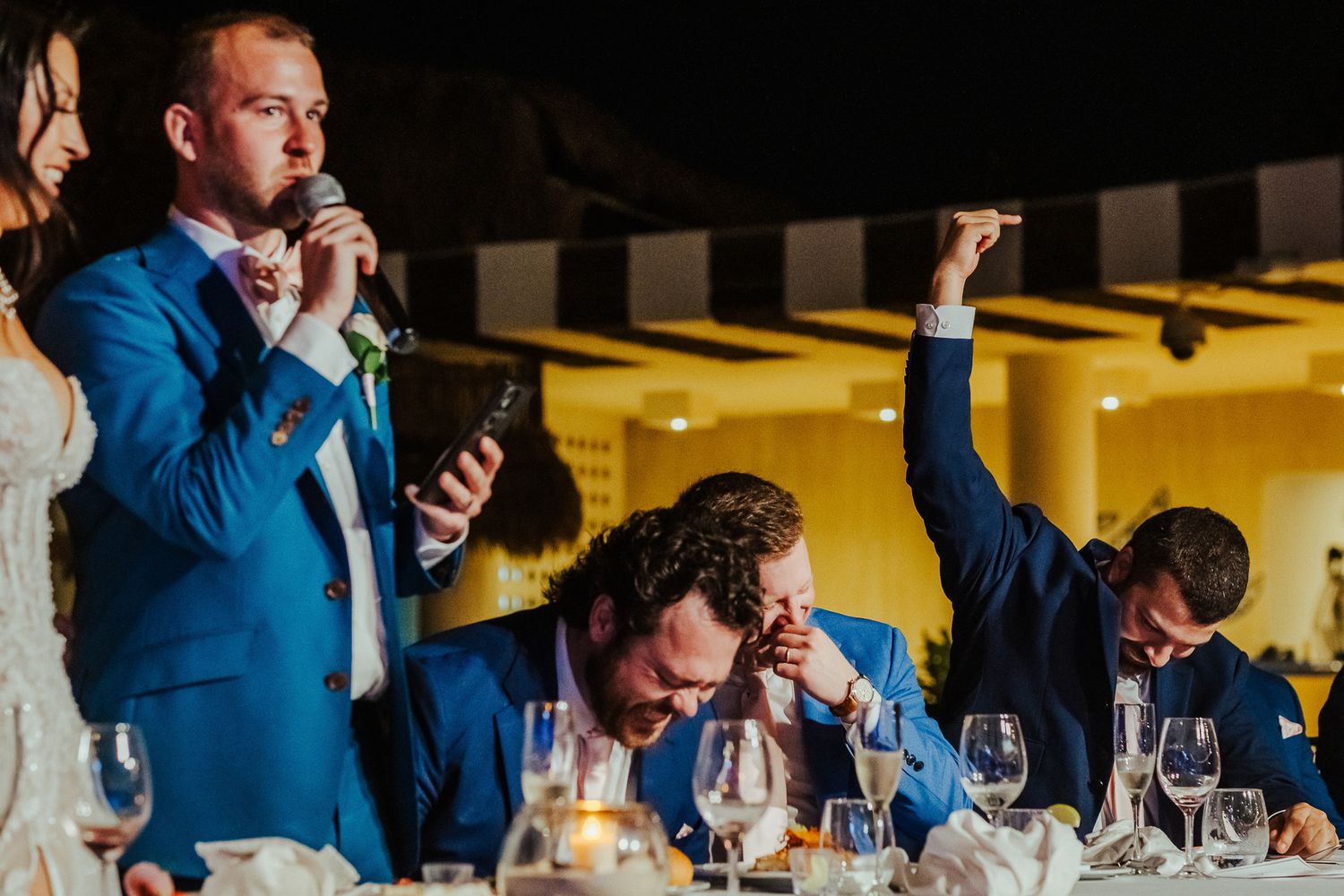 Wedding reception guests reacting enthusiastically during dinner toasts.