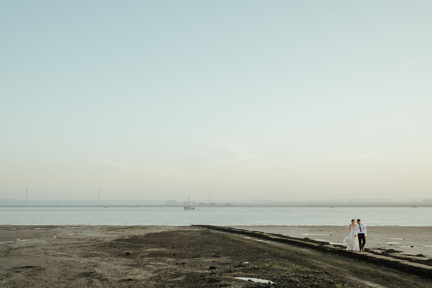 Distant silhouettes on a misty beach during sunset with calm waters in the background.