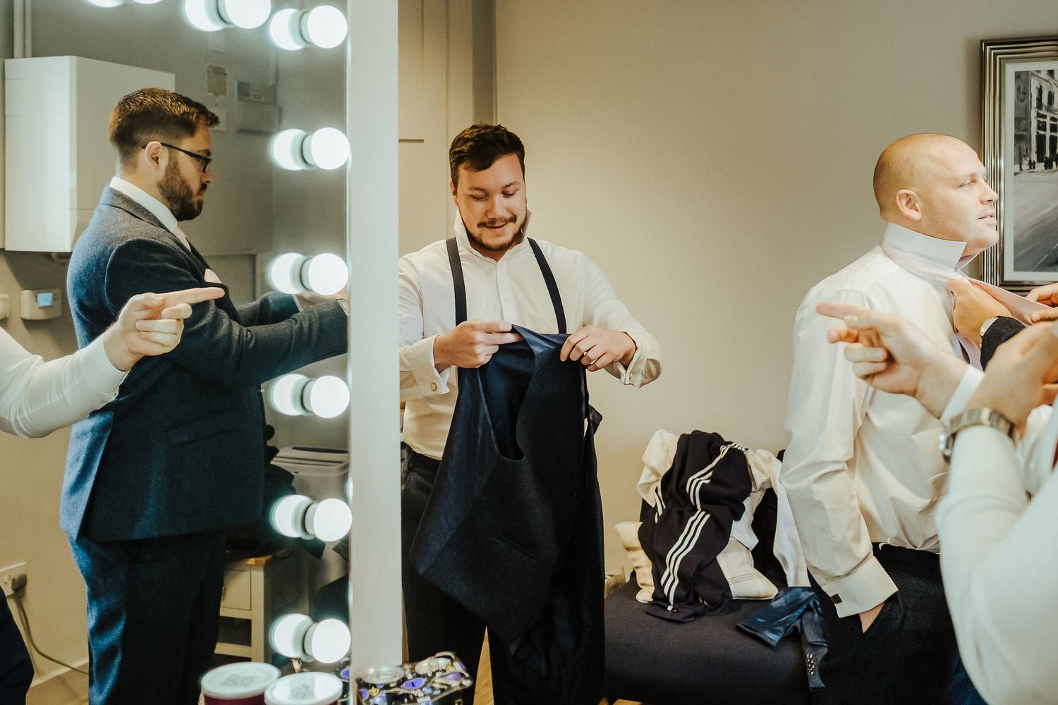 Sequence of people getting ready in a mirrored dressing room with bright lighting.