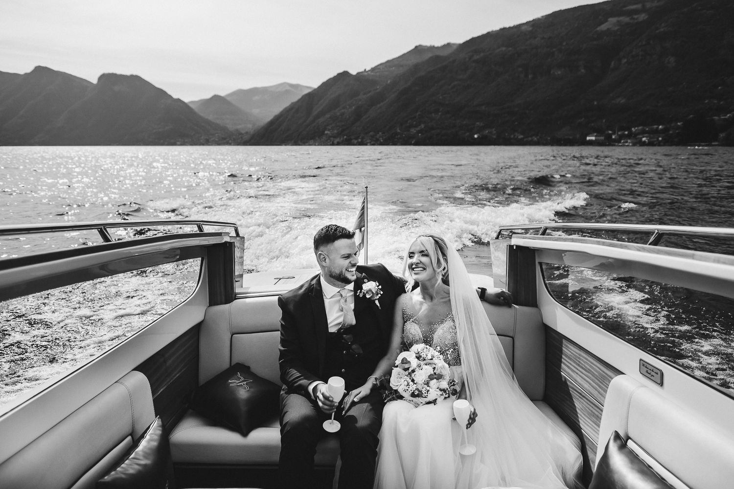 A couple enjoys a boat ride across a scenic mountain lake surrounded by dramatic landscapes.
