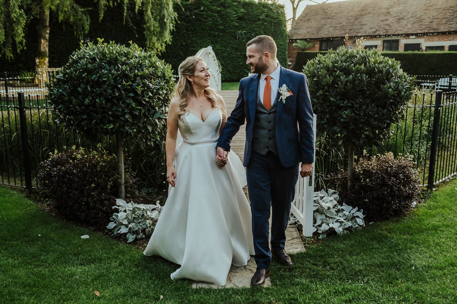 Newlyweds walking through a lush garden pathway after their ceremony.