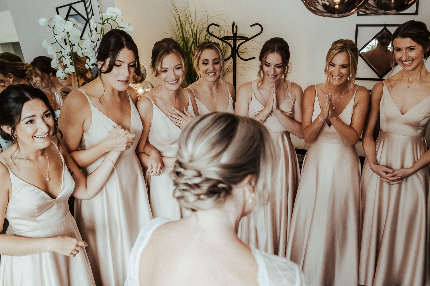 Group photo of bridesmaids wearing matching blush pink dresses standing together.