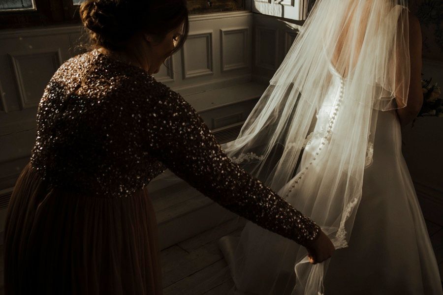 Artistic detail shots of a wedding dress with sparkles and intricate details in low light.