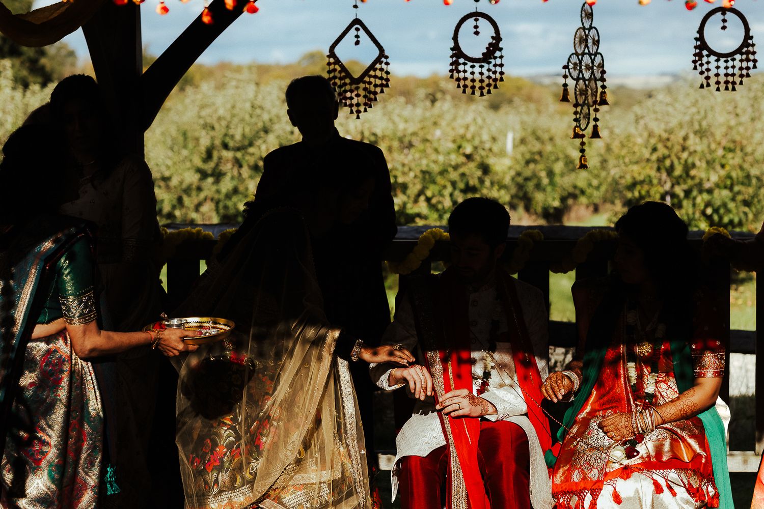 Wedding ceremony setup outdoors with trees and decorative elements in silhouette.