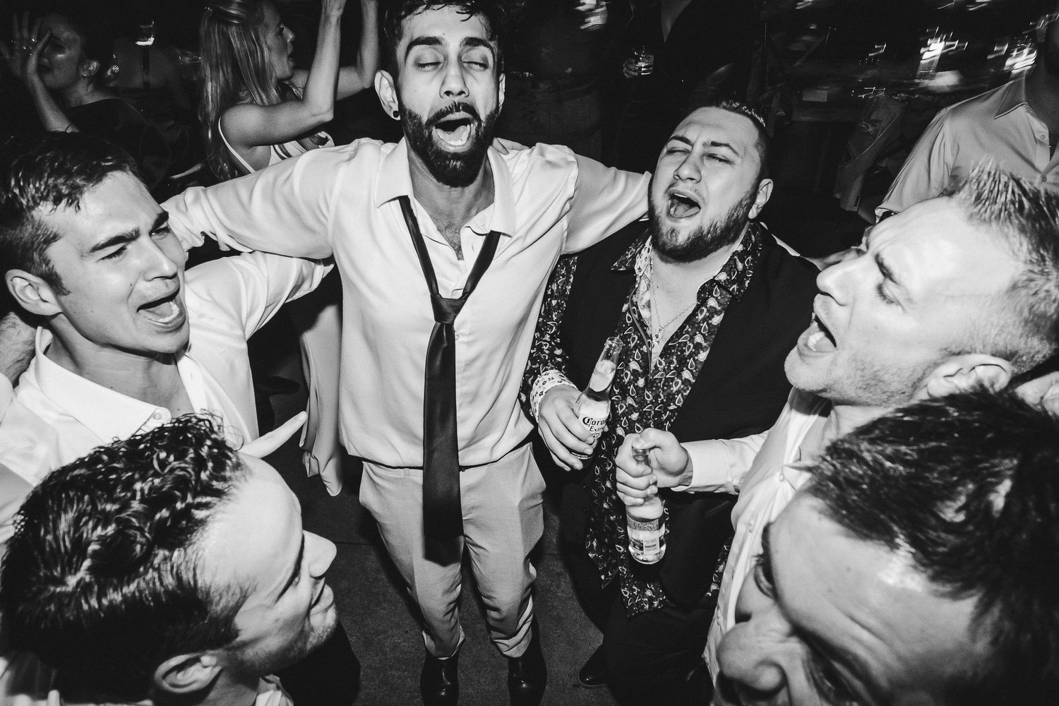 Group of friends singing enthusiastically together at a party in black and white.