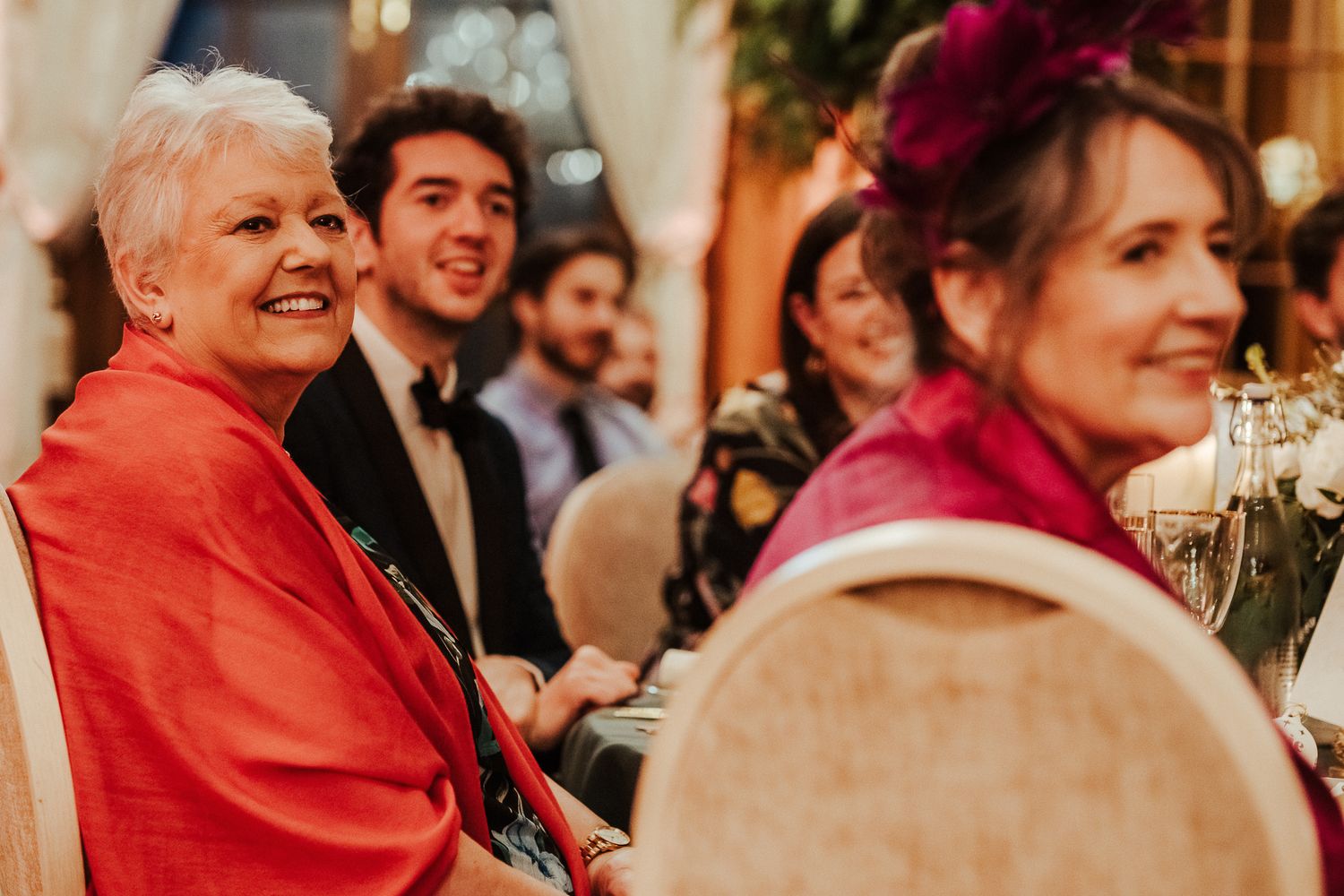 Wedding guests enjoying a lively reception with festive decor and warm lighting.