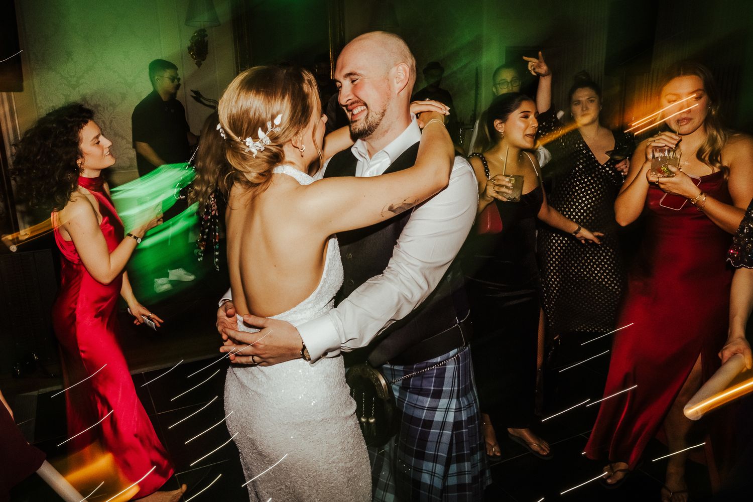 Couples dancing together energetically at a nighttime wedding event.