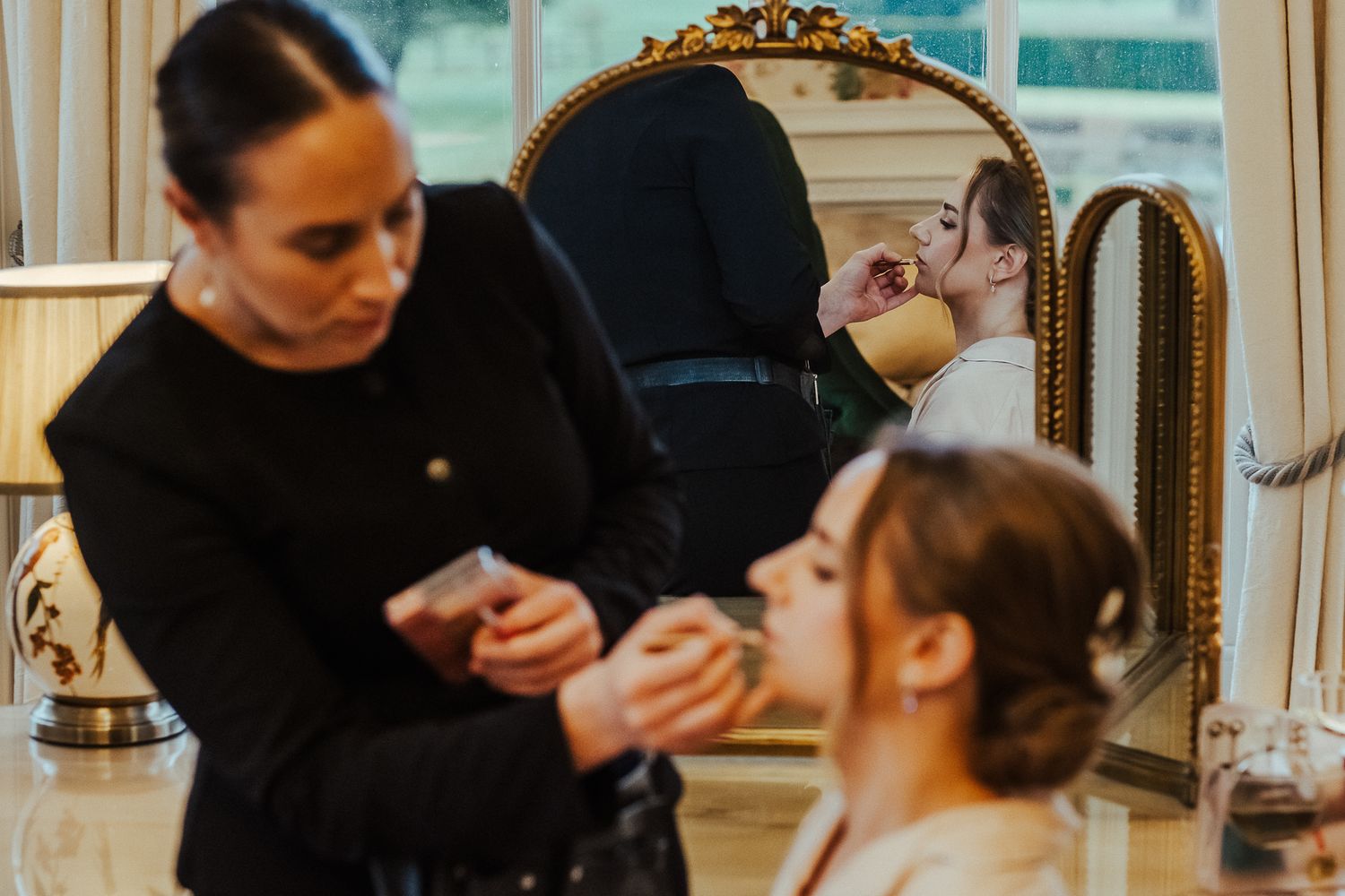 Makeup application and wedding day preparations in a luxurious room with vintage decor.