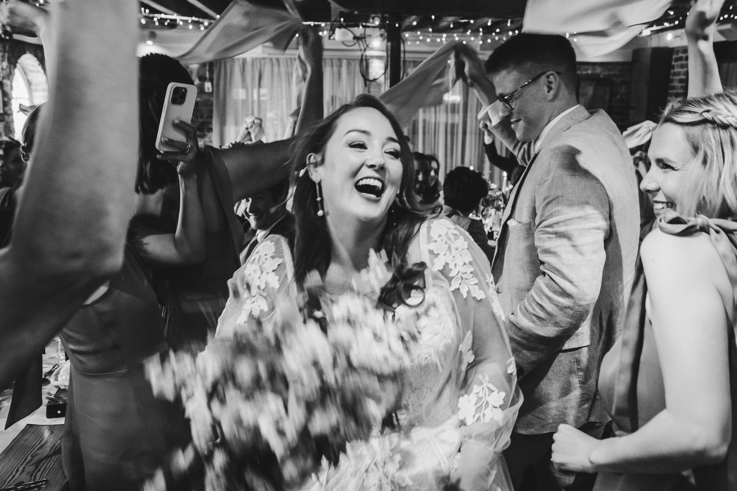Candid black and white photo of bride laughing during wedding celebration.