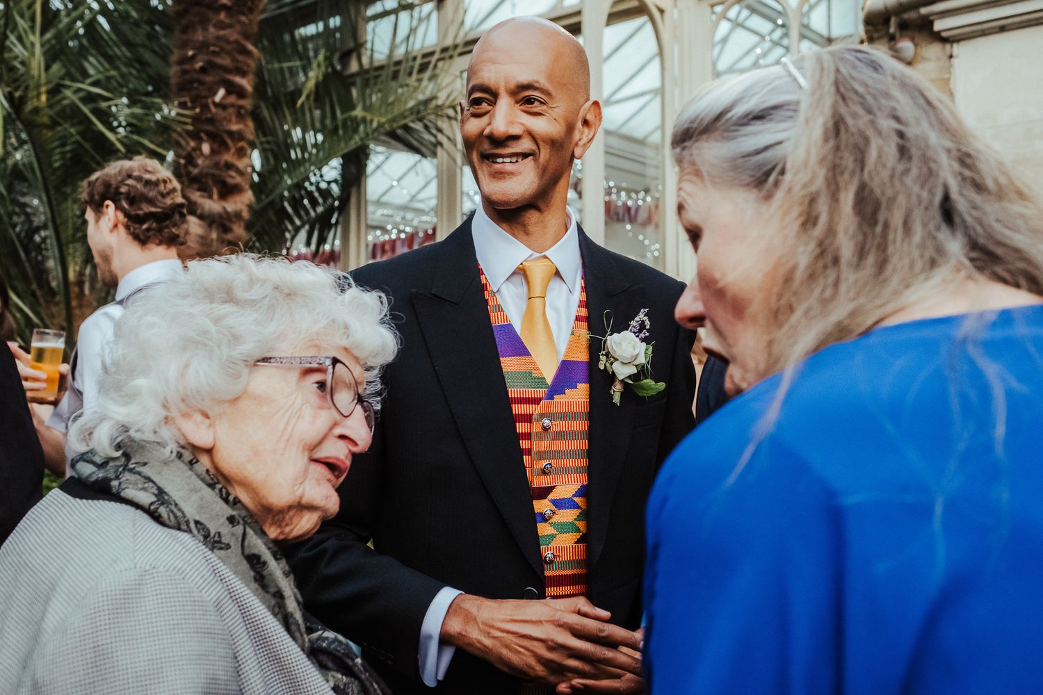 Wedding guests in bright blue and formal attire mingling at an outdoor event.