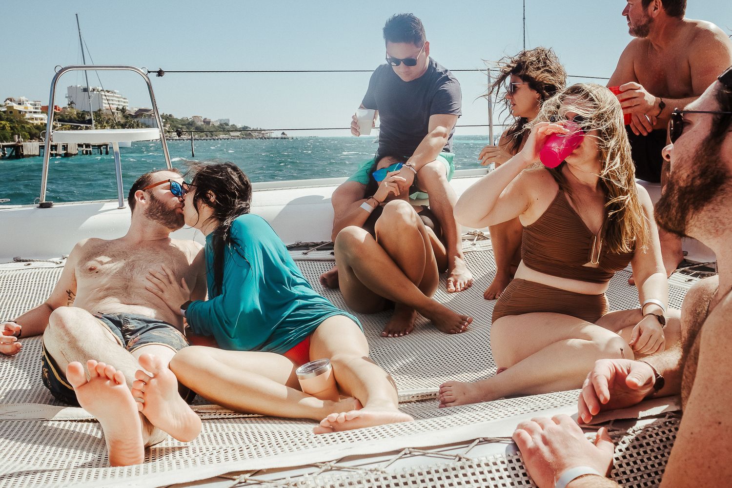 Friends relaxing and socializing on a sailboat deck on a sunny day.