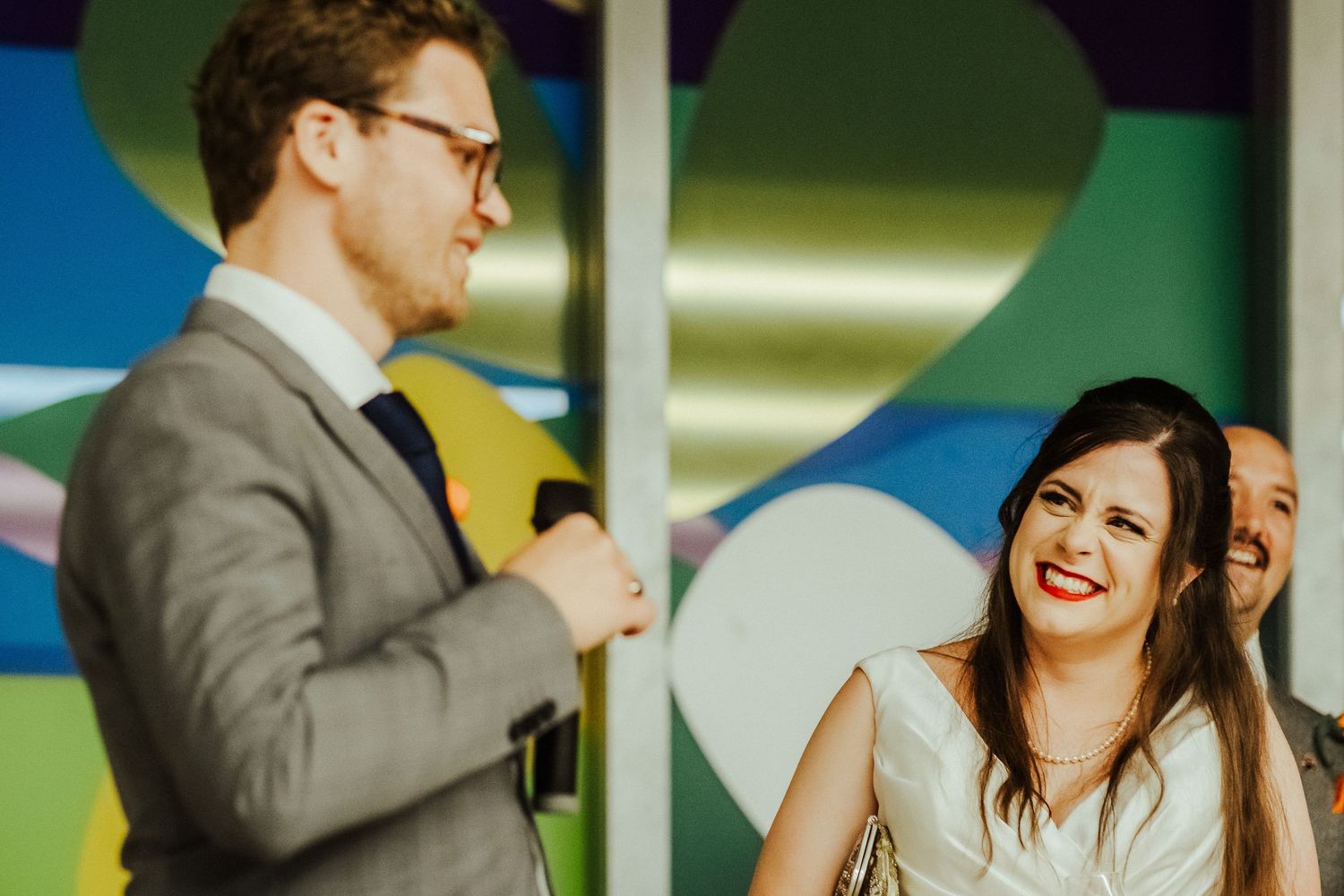 Couple sharing laughter against a vibrant backdrop of colorful geometric shapes.