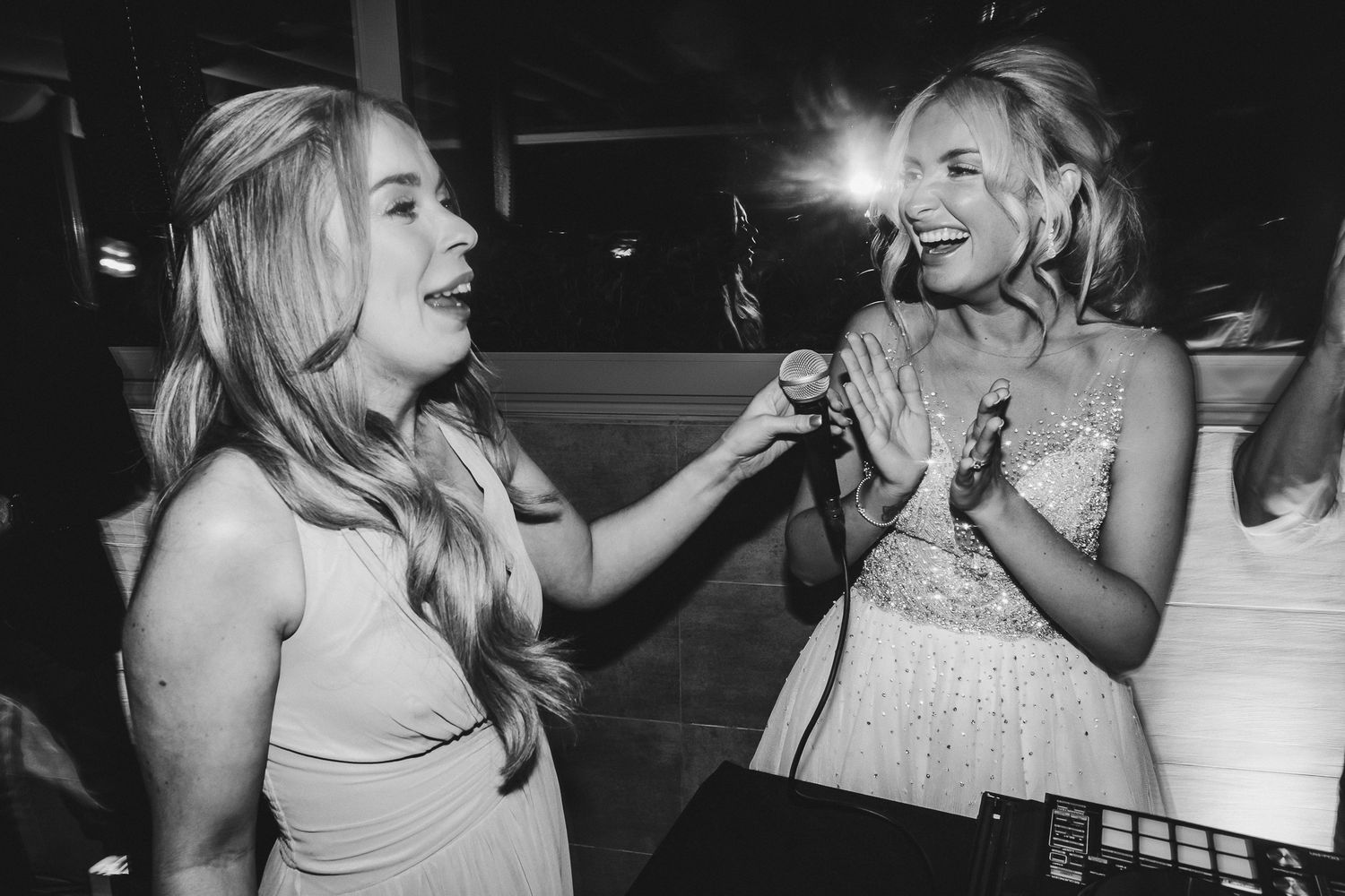 Black and white photo of two guests singing or performing during wedding reception festivities.