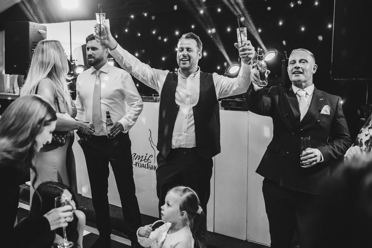 Black and white wedding photo capturing joyful dancing guests celebrating during the reception.