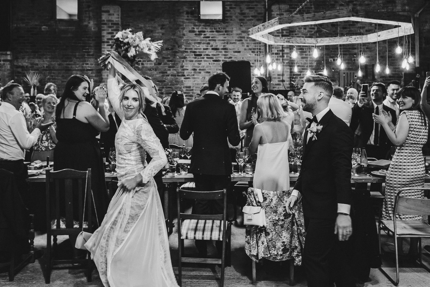 Wedding reception celebration with string lights and exposed brick walls.