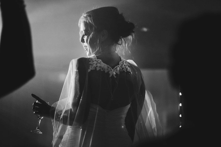 Artistic black and white shot of bride holding wine glass in soft focus.