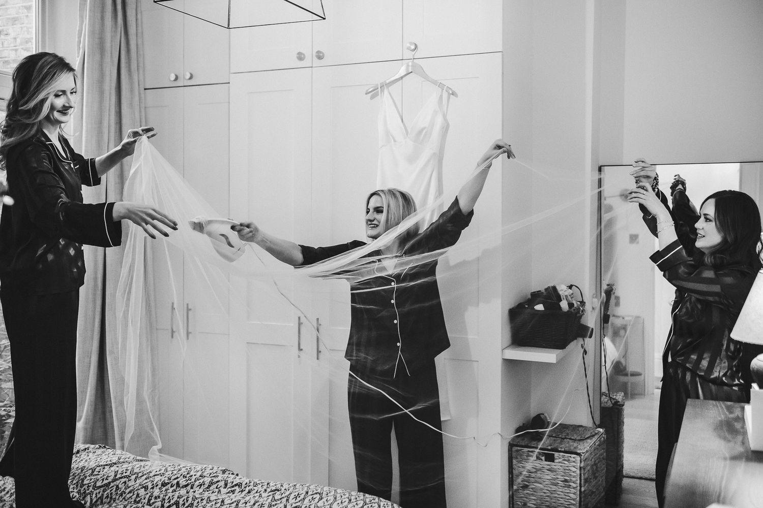 Black and white image of wedding dress preparations in a bright dressing room.
