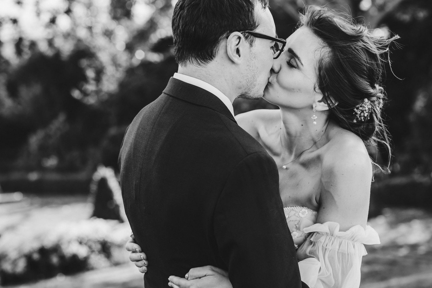 A tender black and white moment between newlyweds sharing their first kiss outdoors.