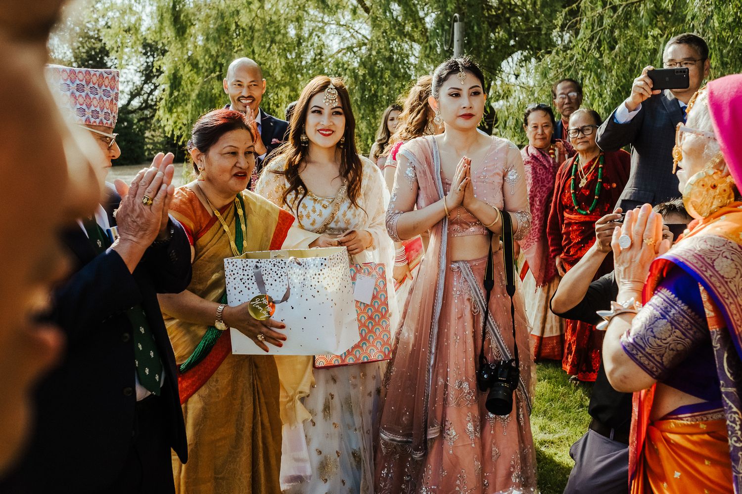 Wedding guests in colorful traditional attire participate in celebration rituals outdoors.