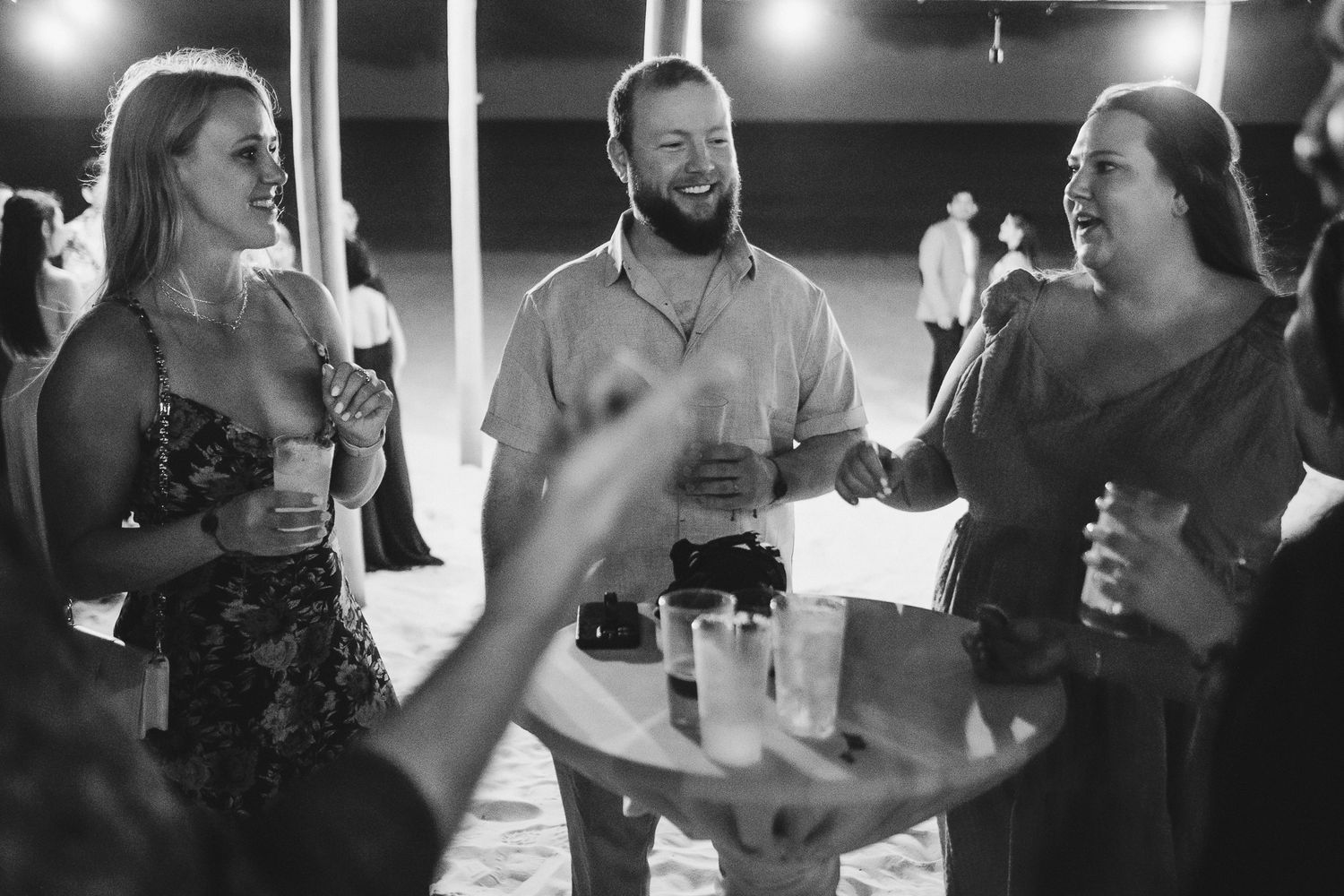 A group of party guests enjoying drinks and conversation at a nighttime gathering.