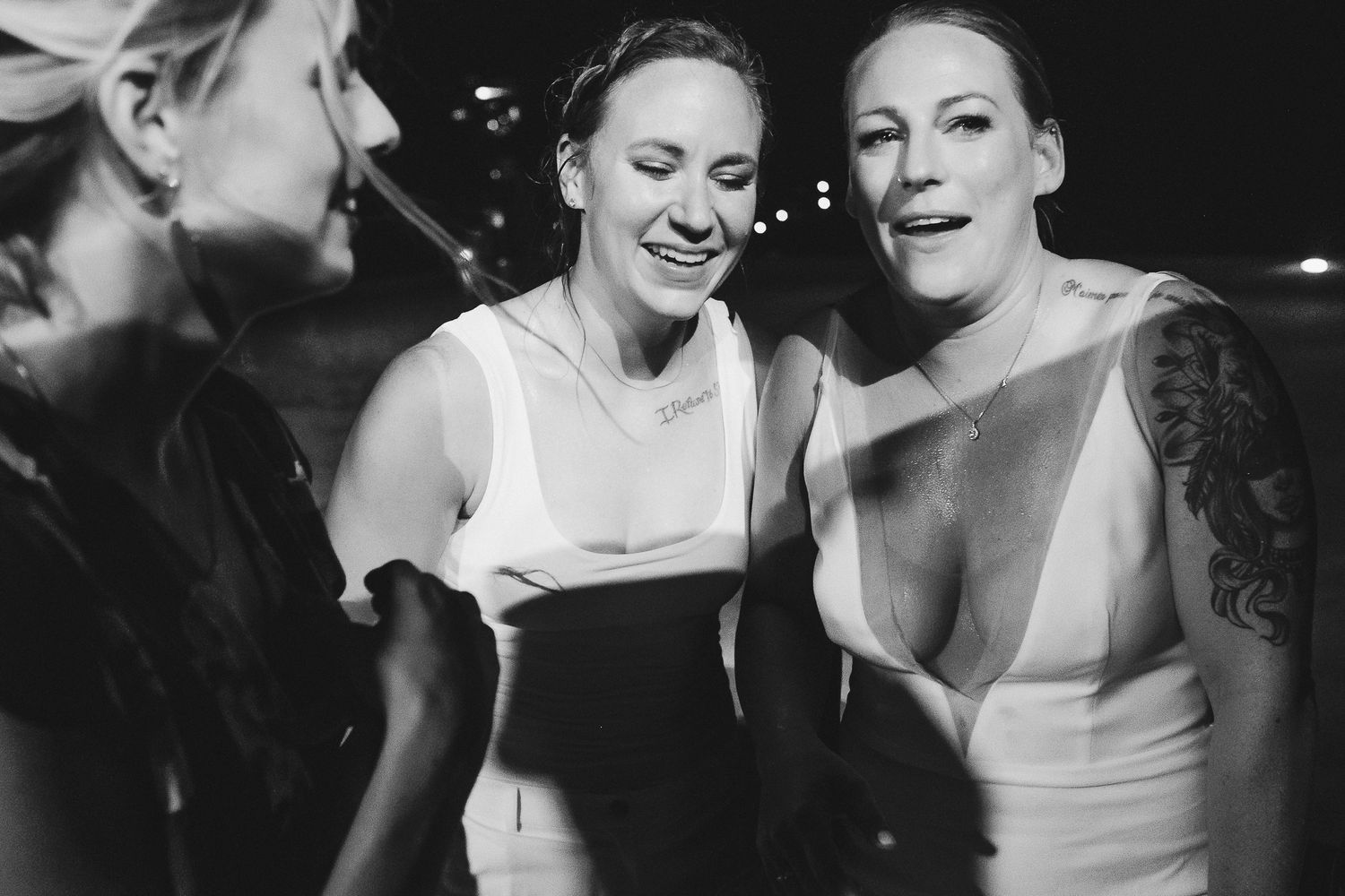 Wedding guests sharing a candid moment of laughter in black and white.