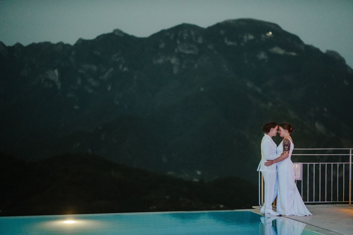 Dramatic coastal mountain backdrop frames couple during twilight wedding photos.