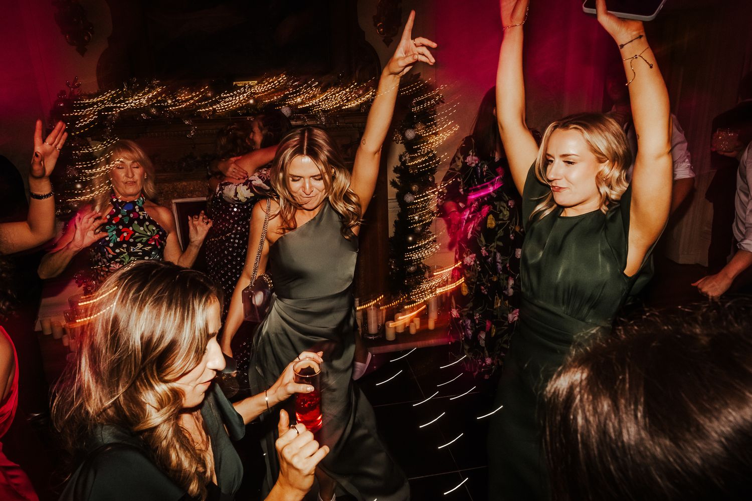 Festive reception dance floor with guests celebrating under dramatic red lighting effects.