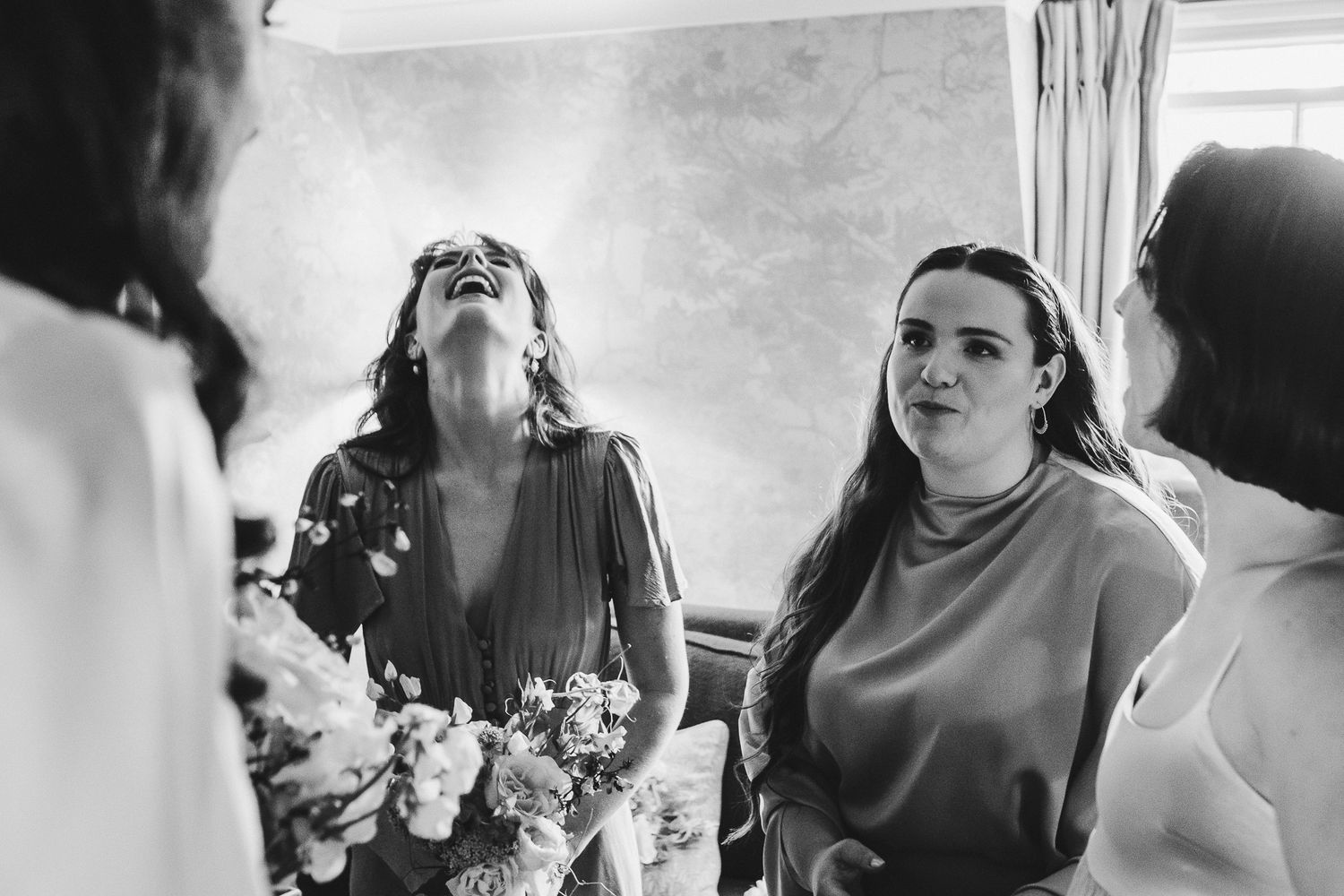Women celebrating together while holding bouquets in a candid wedding moment.