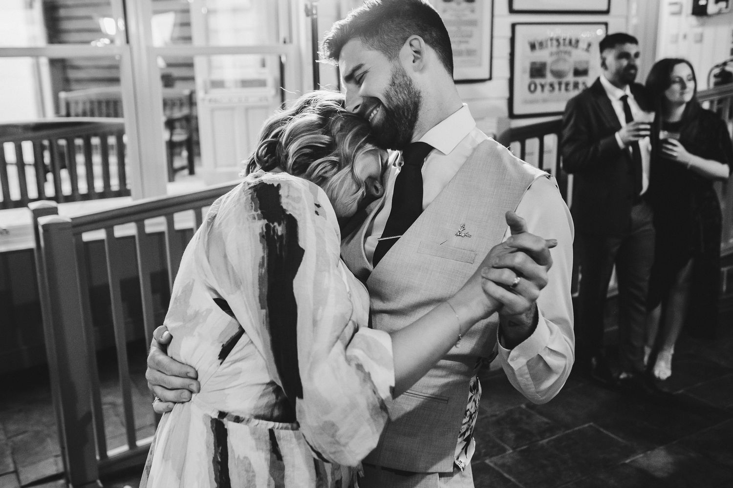 A black and white photo captures a romantic dance moment at a wedding reception.