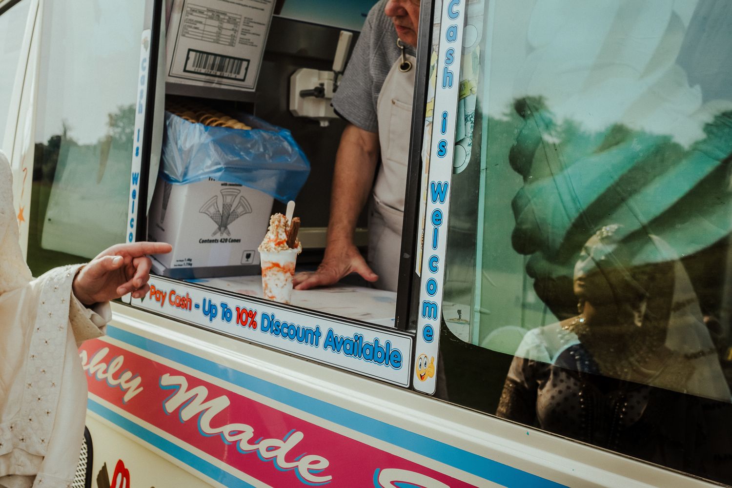 A colorful ice cream truck window with stickers and text reading 'Locally Made' on a sunny day.