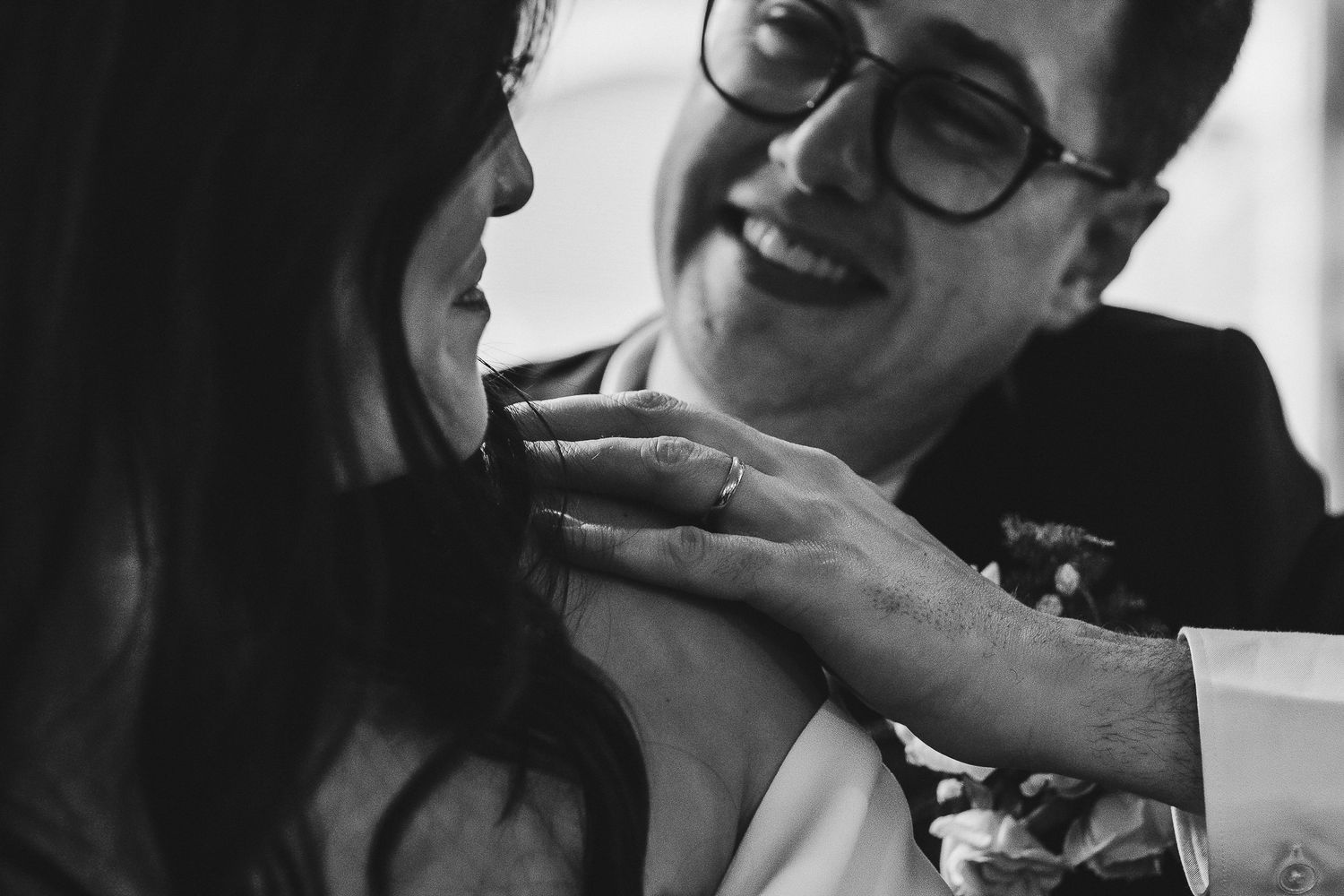 Black and white candid photo showing an intimate romantic moment between a couple sharing laughter in formal attire.