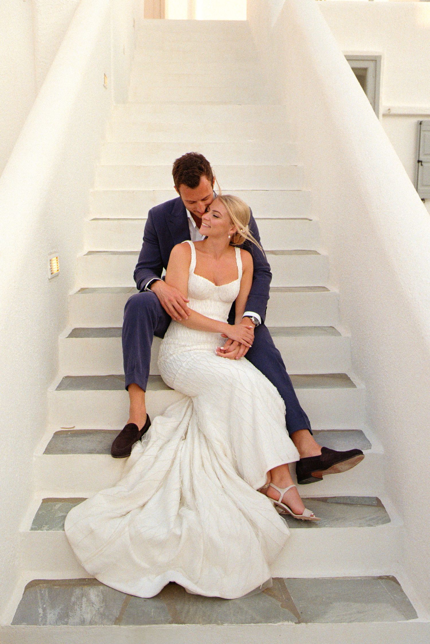 A romantic wedding couple shares intimate kisses while sitting on concrete stairs in a series of candid shots.