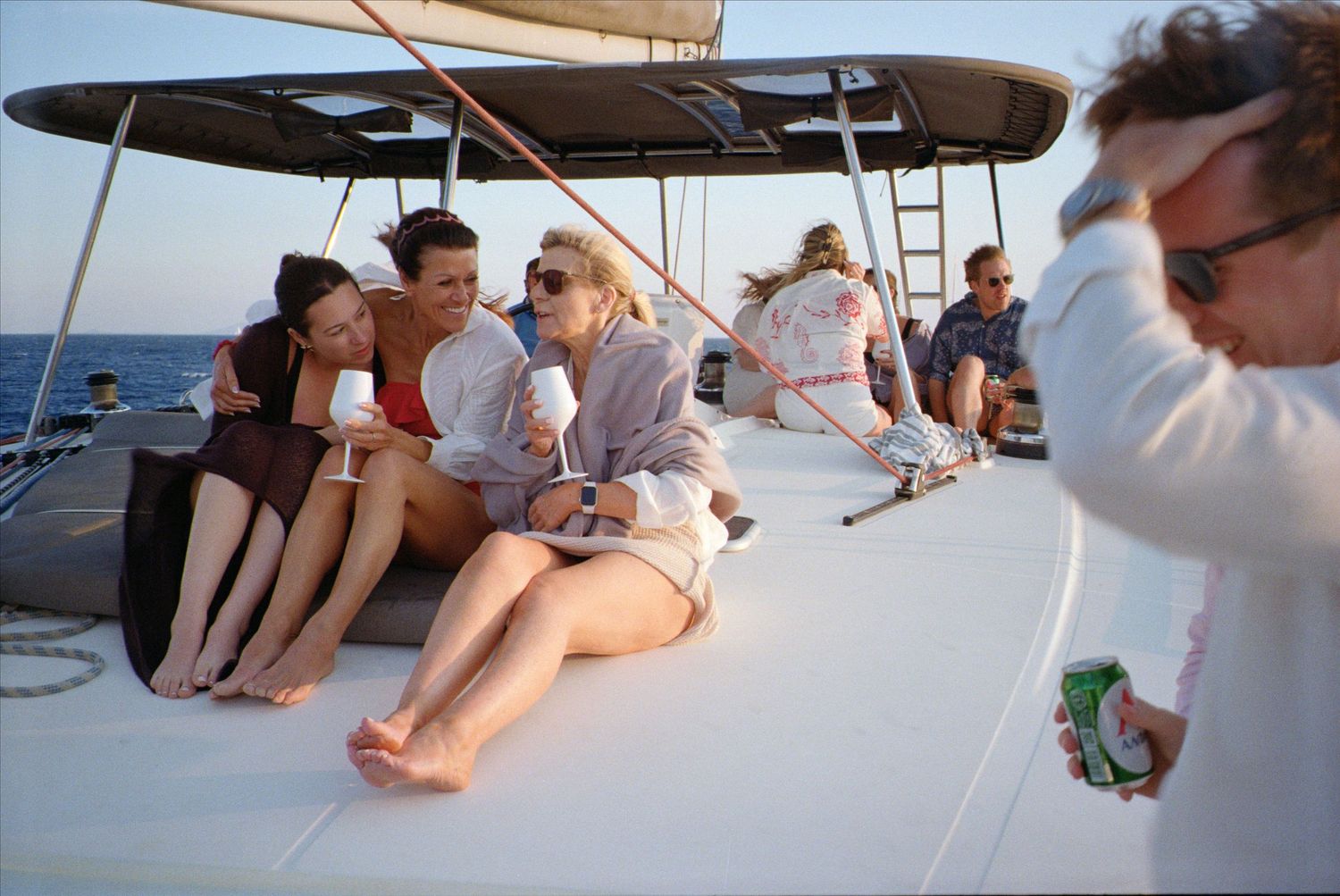 Friends relaxing together on a sailboat deck under blue skies during a leisure cruise at sea.