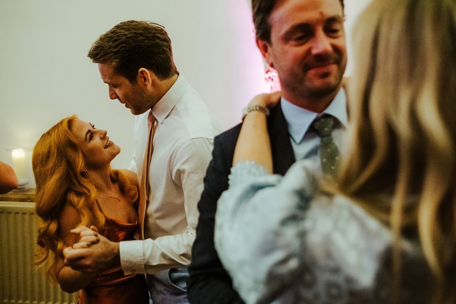 Wedding guests share laughter and intimate moments during a joyful reception celebration.