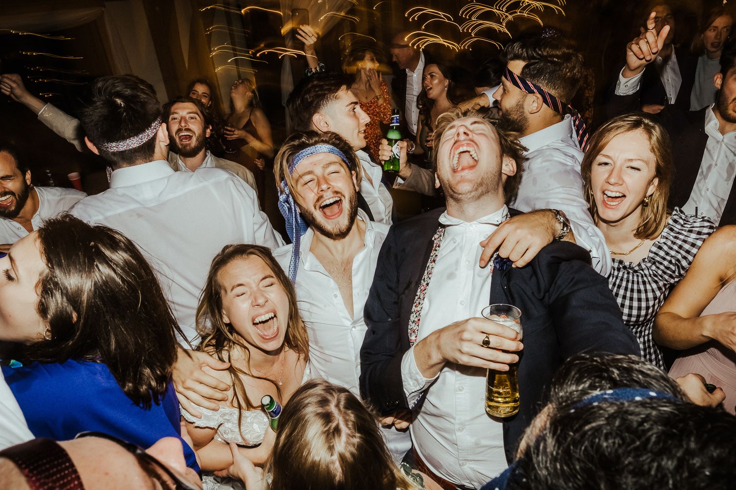 Energetic crowd of wedding guests dancing and celebrating on a packed dance floor.