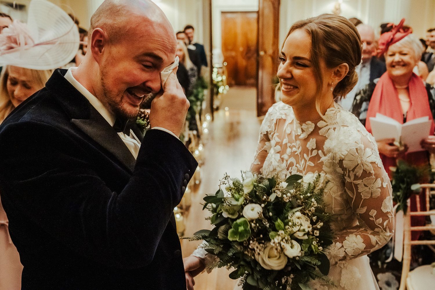 Emotional winter wedding moment with bride holding white and green bouquet.