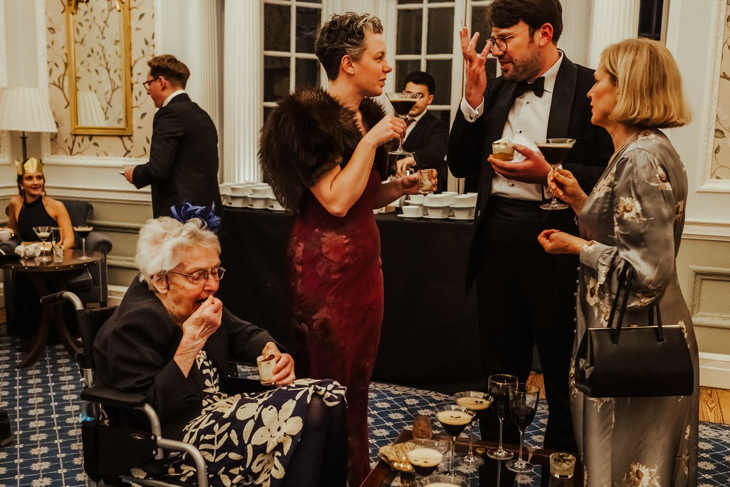 Elegant wedding reception with guests socializing around bar area in formal attire.