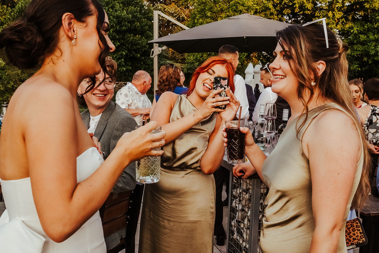 Wedding guests enjoying drinks and conversation during outdoor reception.