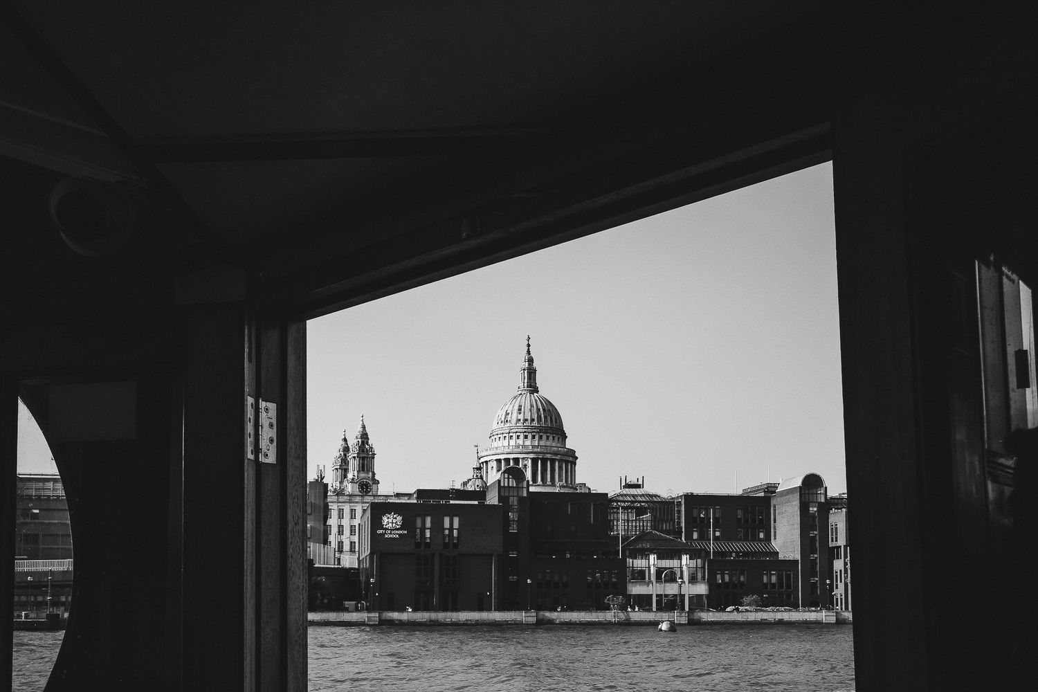 A black and white view of St Paul's Cathedral dome through an archway framing the London skyline.