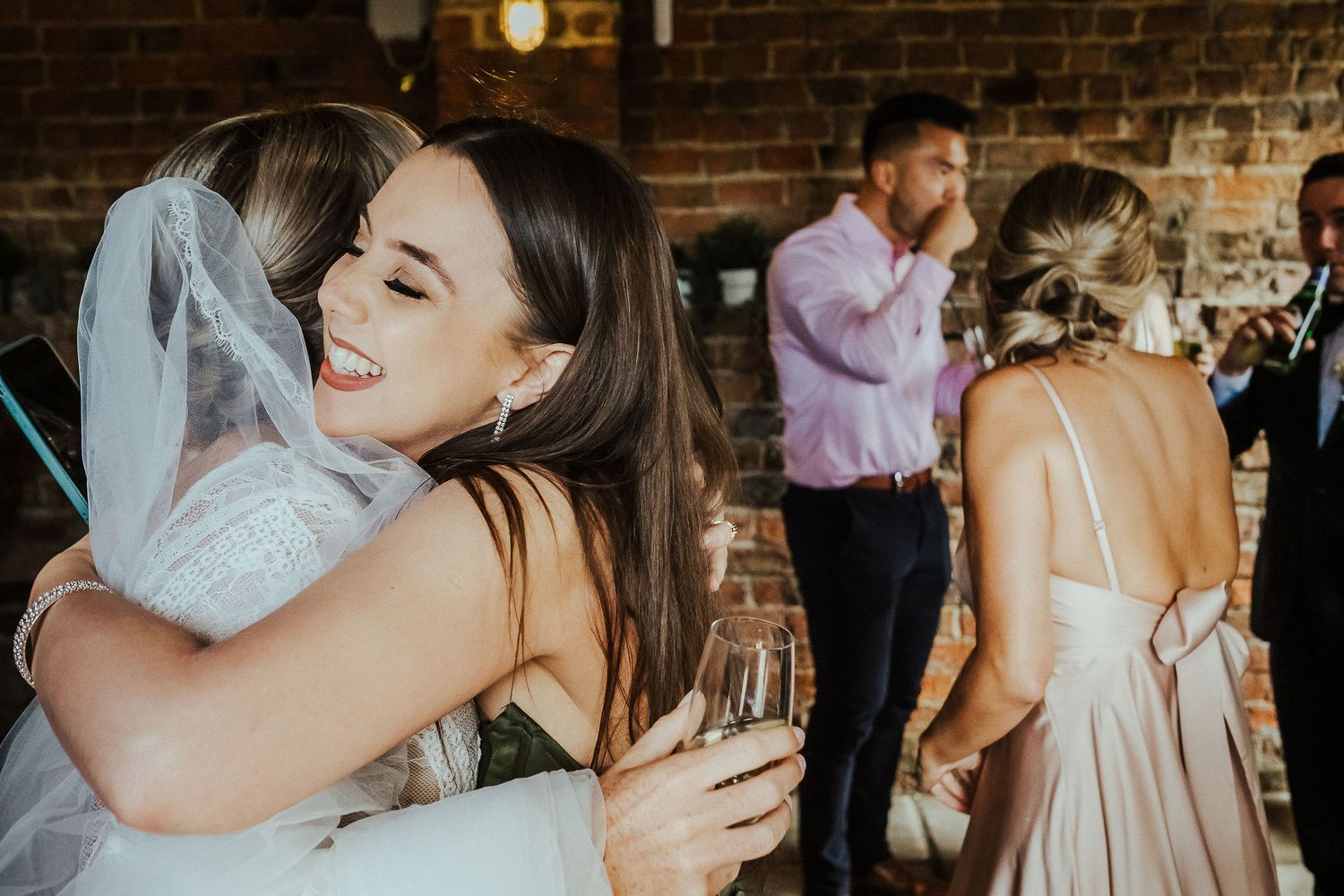 Two people share an emotional embrace at a rustic brick venue during wedding celebration.