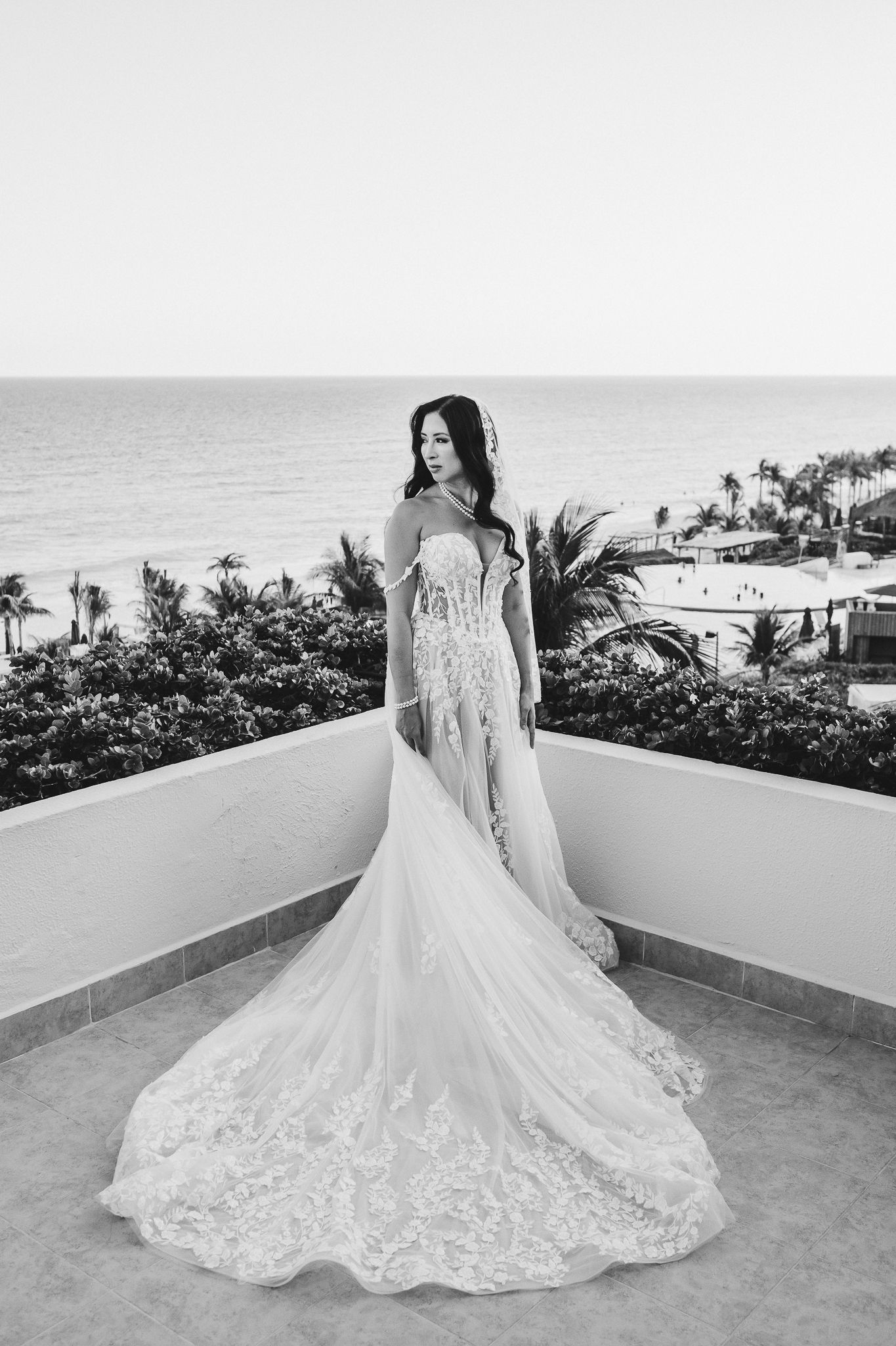 Black and white full length bridal portrait on a tropical balcony overlooking the ocean.