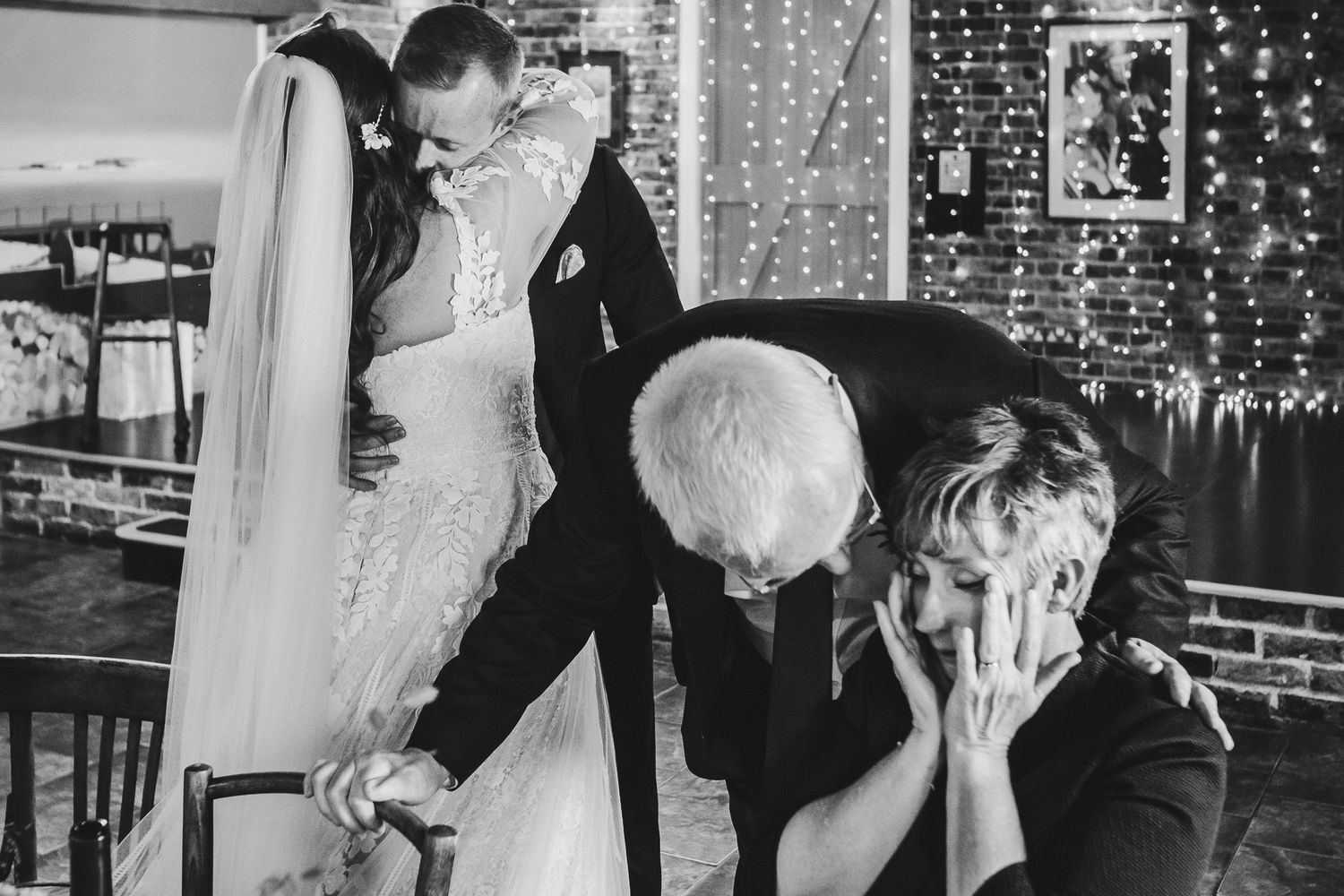 Emotional wedding moment captured with couple embracing while others react with visible emotion in background.