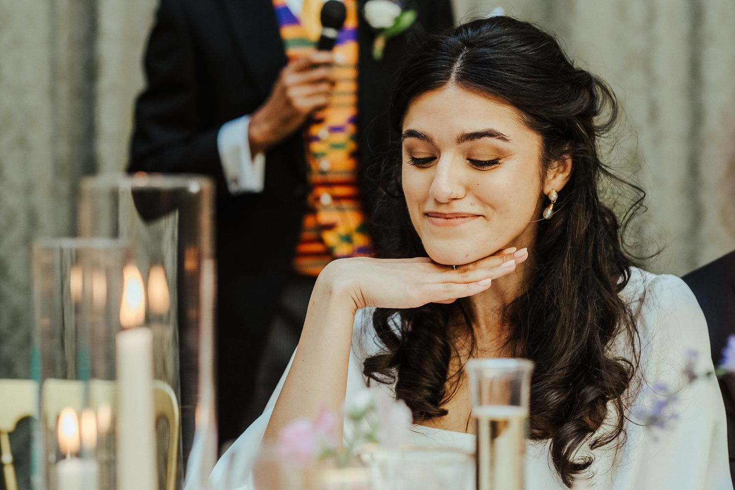 Candlelit portrait of bride at reception table with elegant decor.