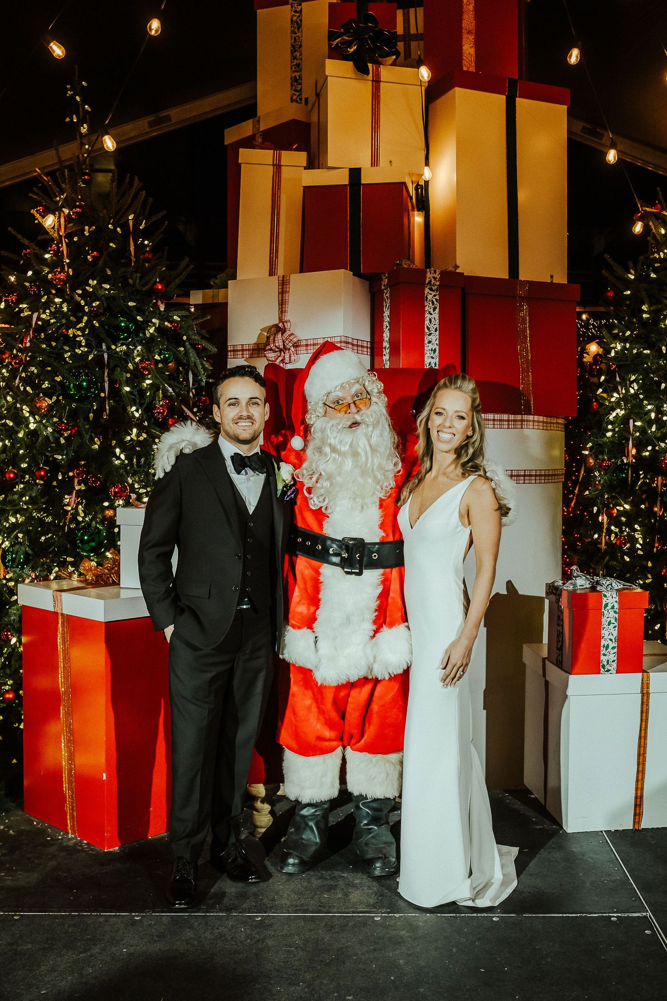 A festive holiday scene with Santa Claus and decorated Christmas trees and wrapped presents.