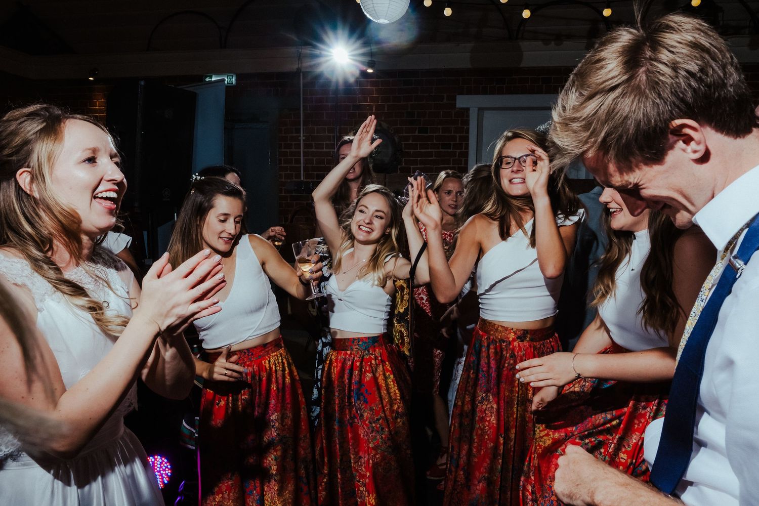Wedding celebration with dancing and laughter in a dimly lit indoor venue.
